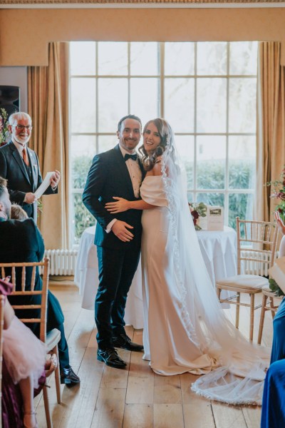 bride and groom stand at top of alter while guests clap