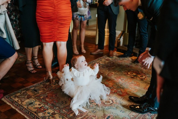 little girl in white dress stands smiling