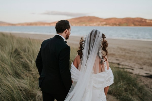 bride and groom embrace and hug on the beach and sand they walk away