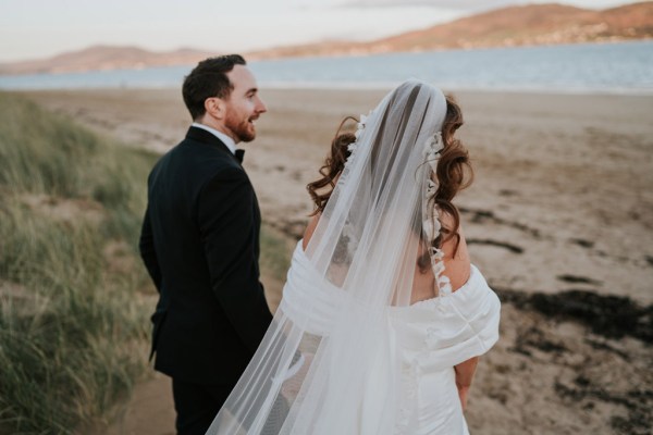 bride and groom embrace and hug on the beach and sand they walk away