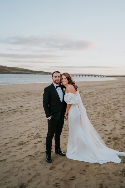 bride and groom embrace and hug on the beach and sand