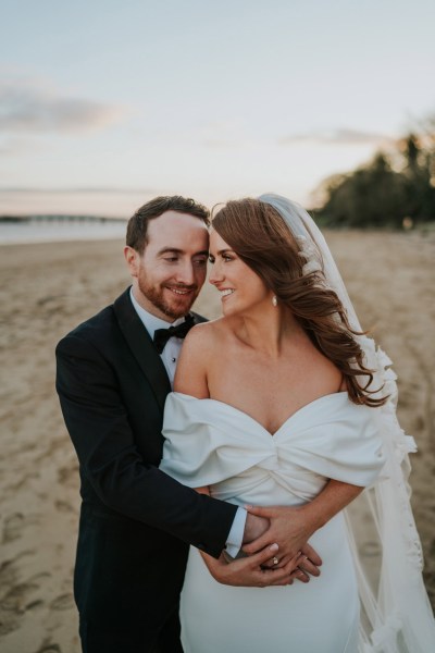 bride and groom embrace and hug on the beach and sand