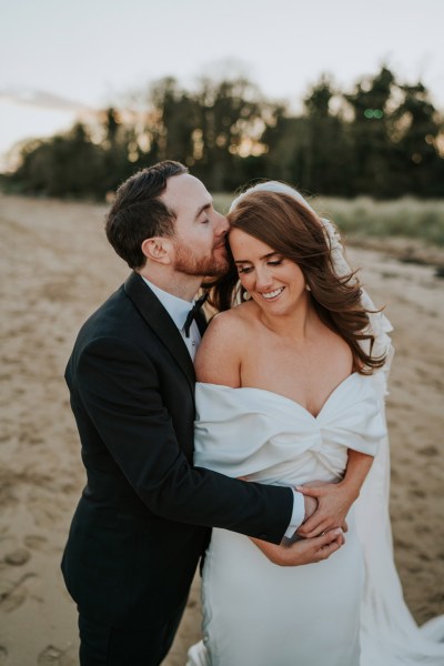 bride and groom embrace and hug on the beach and sand