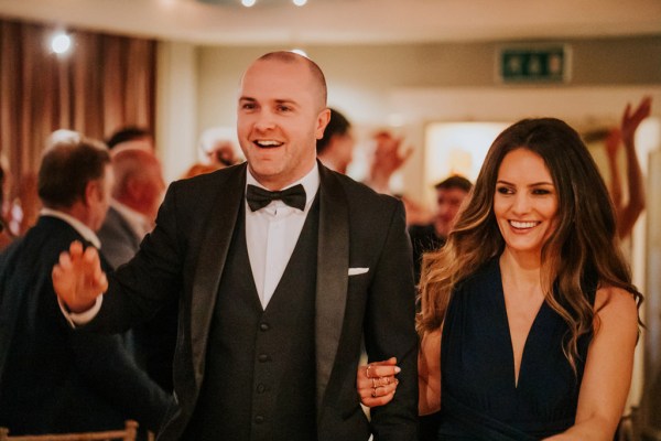 groomsman and bridesmaid enter ballroom with clapping guests