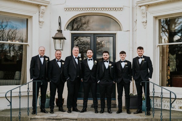 groom and groomsmen pose outside wedding venue