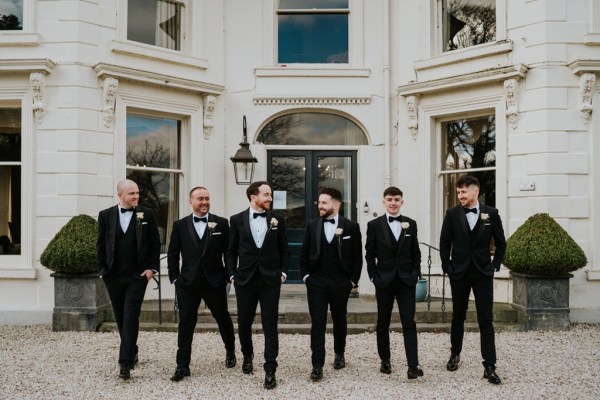 groom and groomsmen pose outside wedding venue