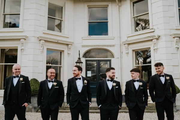 groom and groomsmen pose outside wedding venue