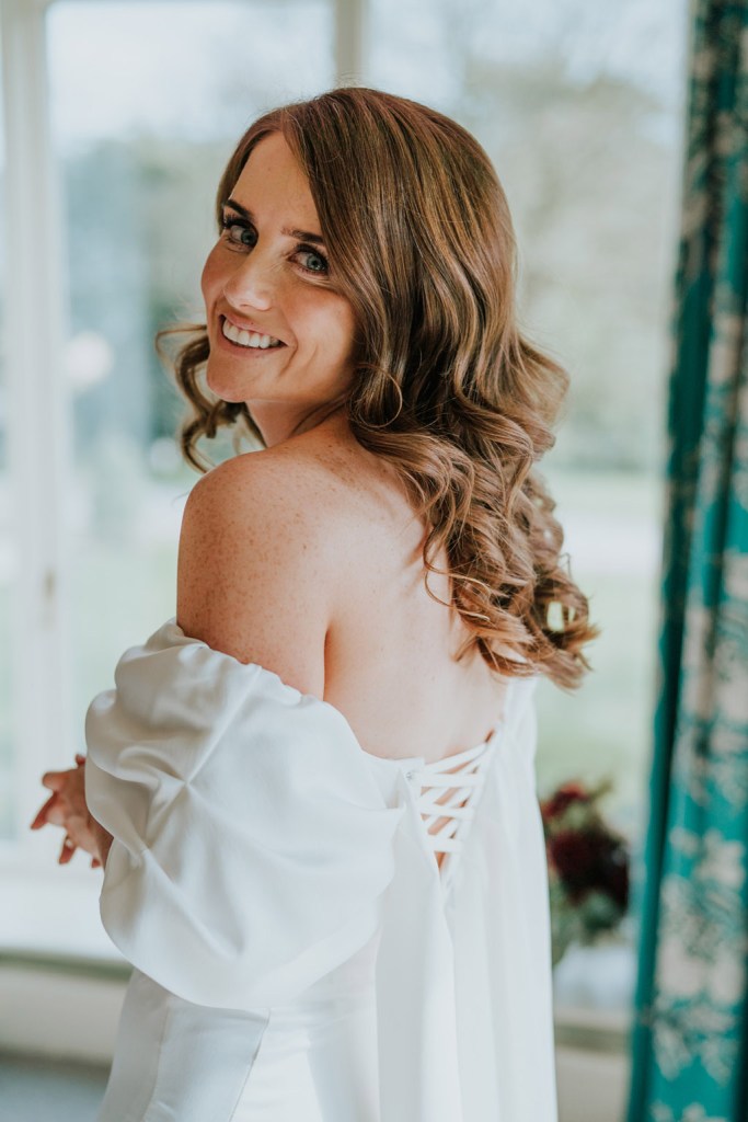 back of brides dress laces up and puffy bridal sleeves dress bride looks over shoulder