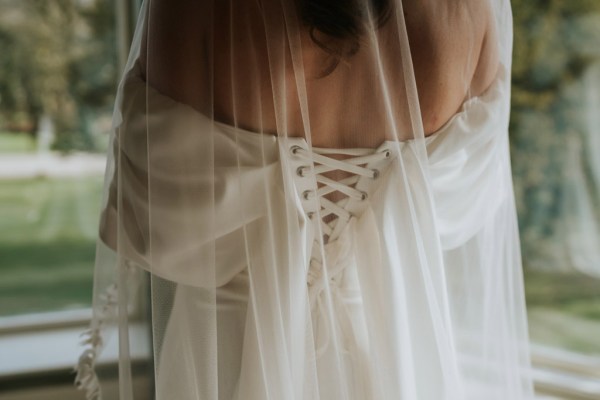 back of brides dress laces up and puffy bridal sleeves dress covered by veil