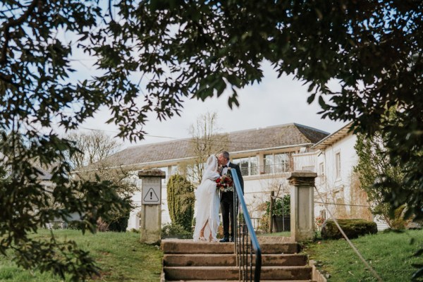 bride and groom kiss at top of garden steps