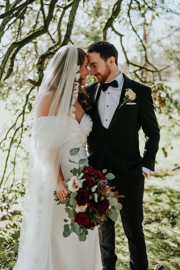 bride and groom embrace touch heads in garden