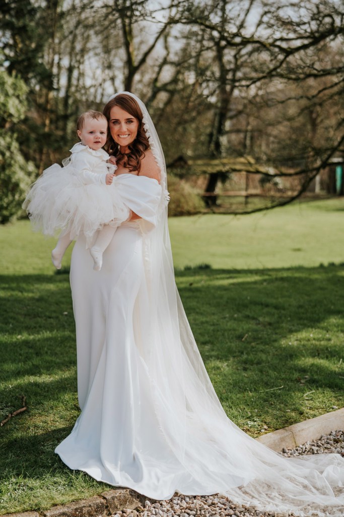 bride mother and daughter pose for a photo in front of grass