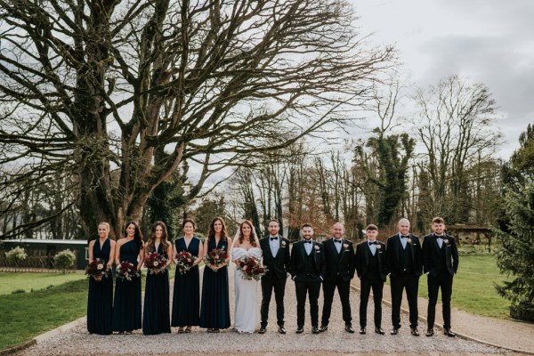 bride bridesmaids groomsmen and groom all pose in a row together