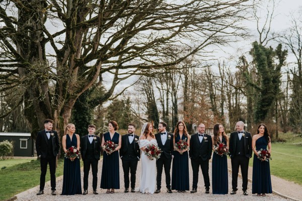 bride bridesmaids groomsmen and groom pose in courtyard to wedding venue they walk