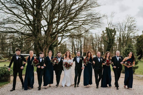 bride bridesmaids groomsmen and groom pose in courtyard to wedding venue they walk