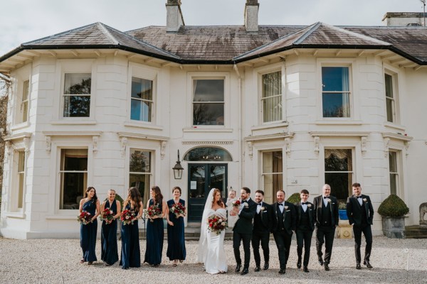 bride bridesmaids groomsmen and groom pose in courtyard to wedding venue