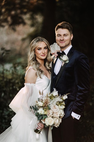 bride and groom face the camera smiling in garden