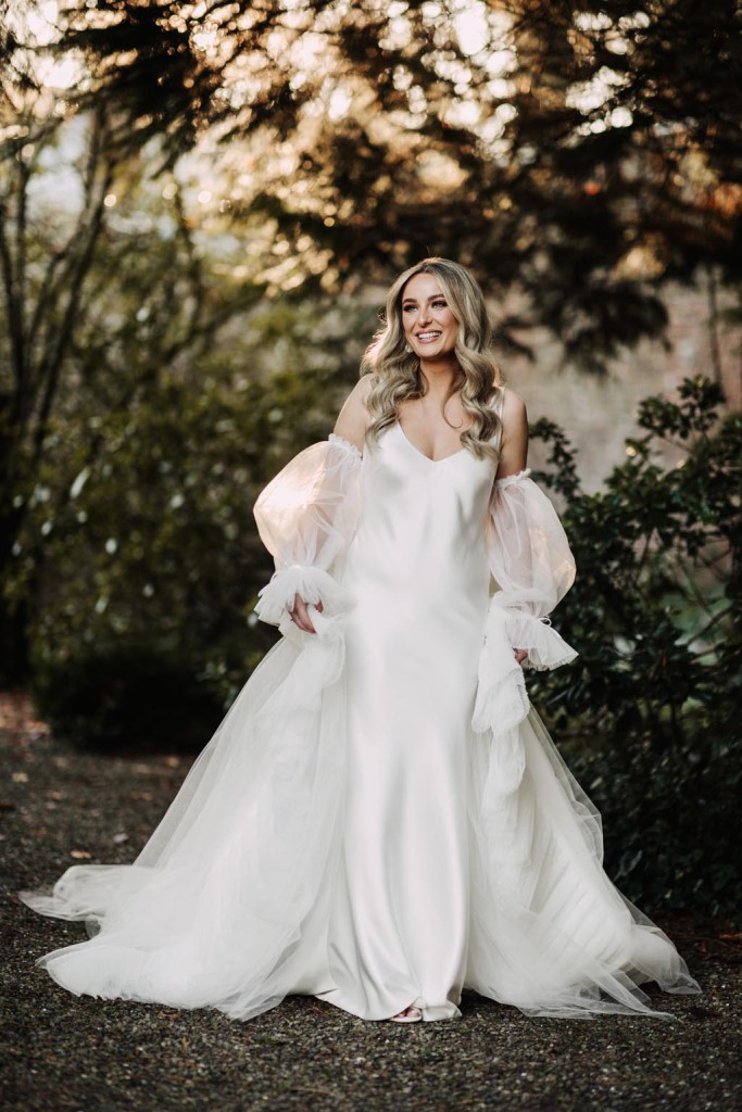 bride stands on her own in garden smiling