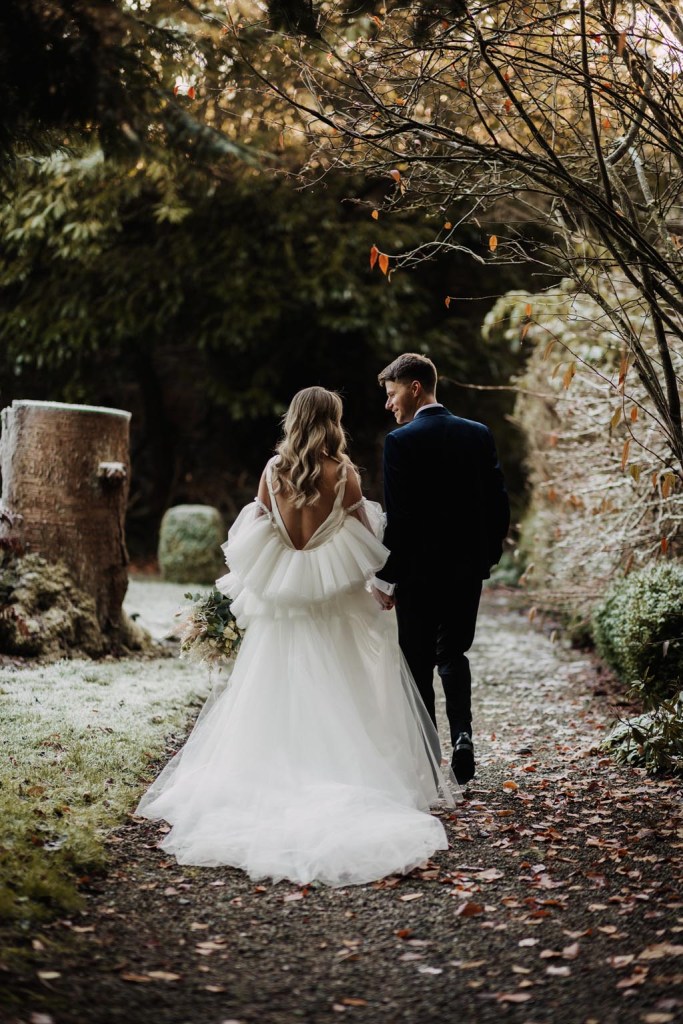 bride and groom walk on the frosty grass in garden