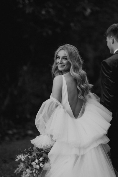 black and white shot of bride looking over shoulder holding bouquet