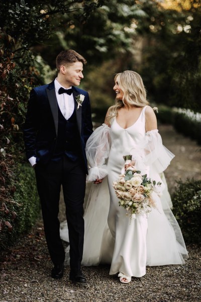 bride and groom look at each other in garden she holds bouquet