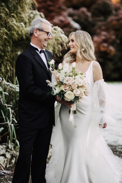 father of the bride and bride look at each other snowy frosty setting