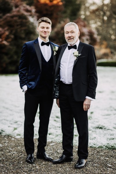 groom and his father pose in front of frosty snowy grass setting