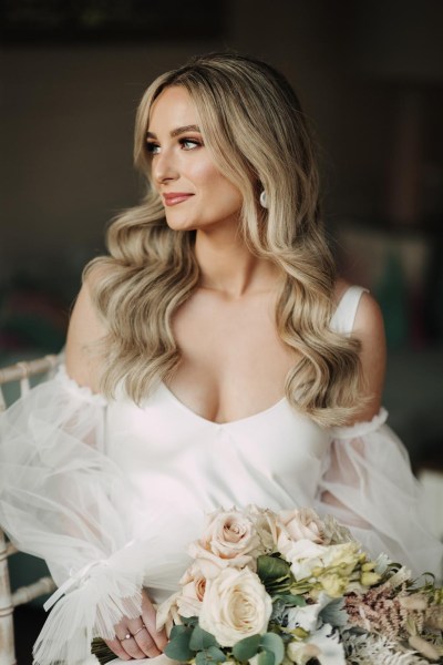 smiling bride looks to one side and is ready holding bouquet