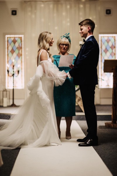 bride and groom hold hands at the alter in front celebrant