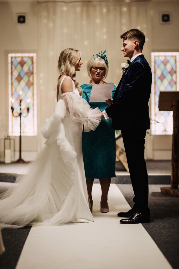 bride and groom hold hands at the alter in front celebrant