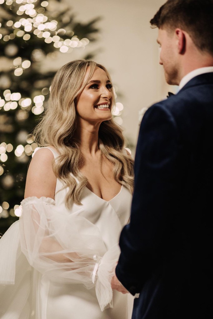 lights in the background of bride and groom at alter smiling at each