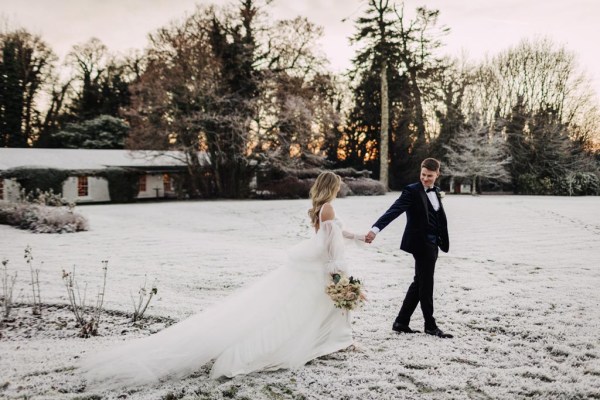 bride and groom standing on snow they walk she holds bouquet