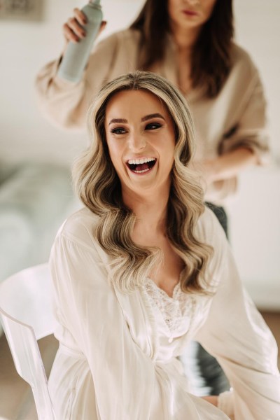 bride getting her hair done and laughing at the same time