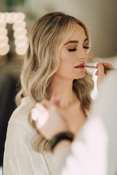 bride gets her makeup done wavy blonde hair