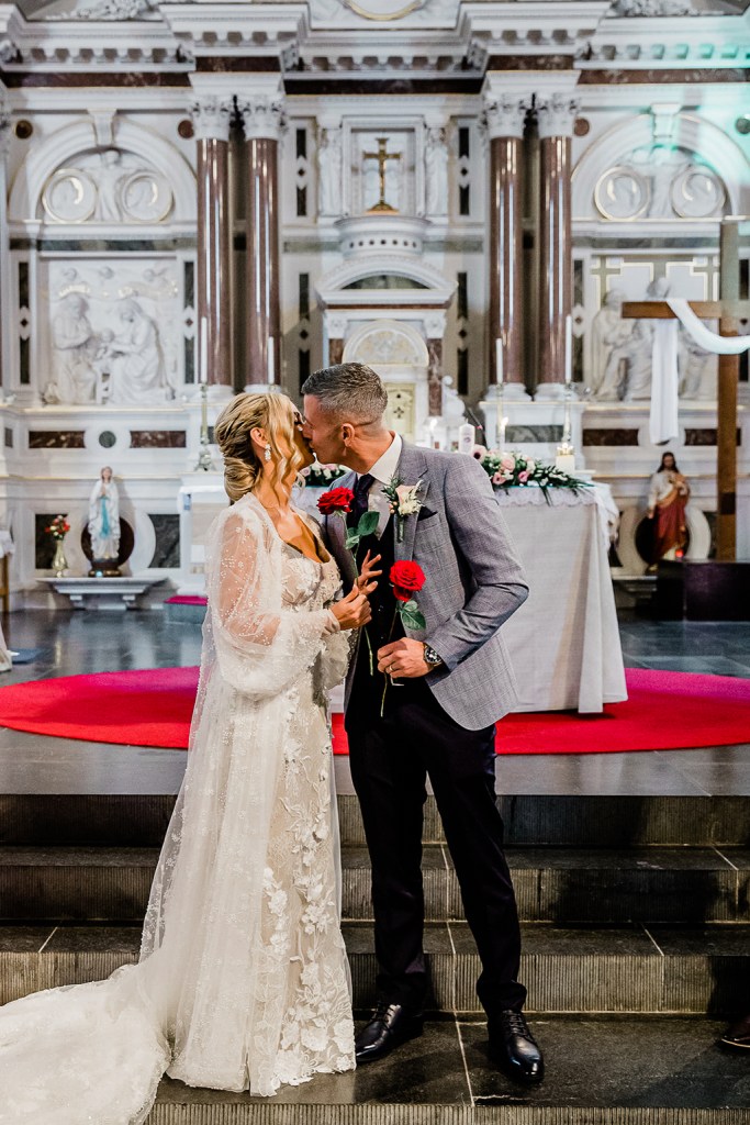 groom leans in to kiss bride interior church chapel setting