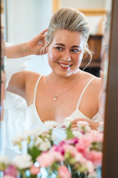 Bride looks at herself in the mirror on Airbnb wedding morning