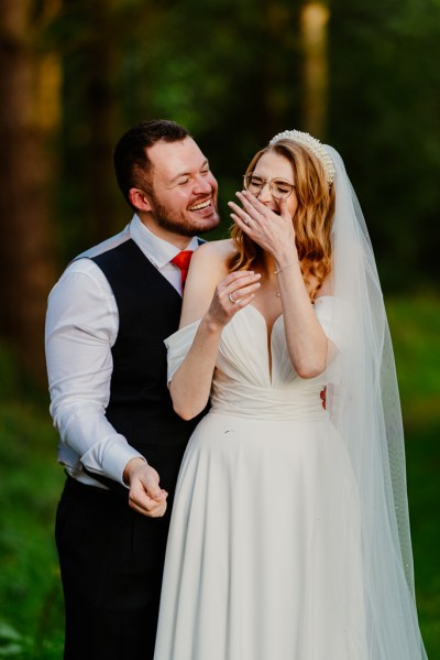 Bride and groom laugh during rustic barn wedding