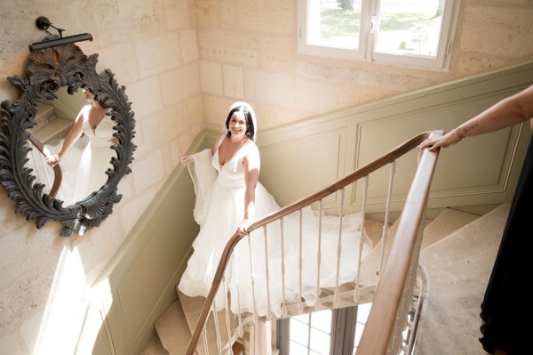 Bride walks down a flight of stairs during black-tie chateau wedding in France